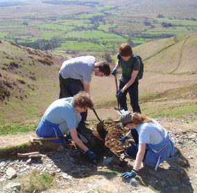 Young Ranger Tom Blackburn with other volunteers clearing drains on the paths up to Blencathra