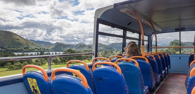 Travellers on an open top bus with Ullswater lake and fells in the distance
