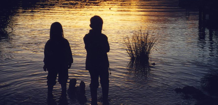 Children paddling at sunset
