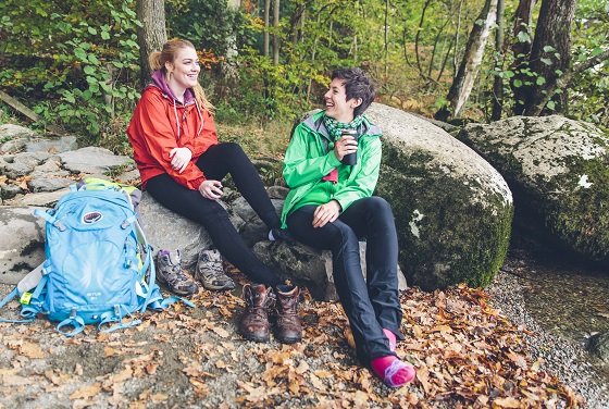 Two walkers enjoying a drink sitting by a lake shore