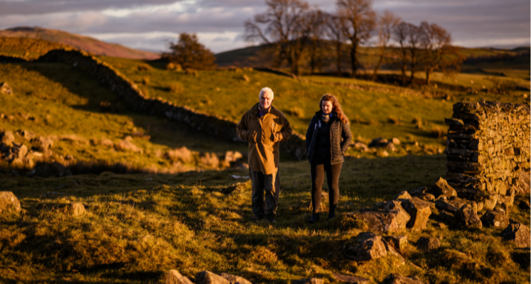 A farming officer walking across a fell talking with a local farmer