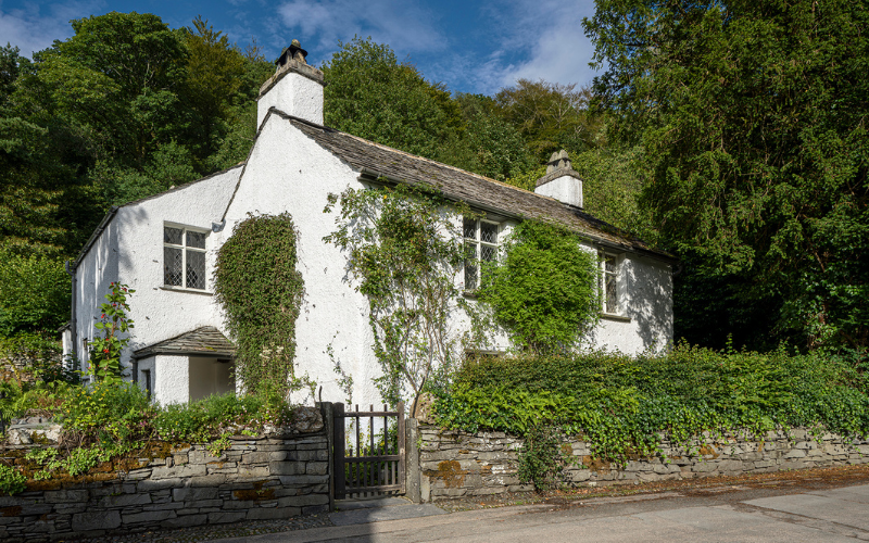 Whitewashed cottage with ivy growing up walls. 