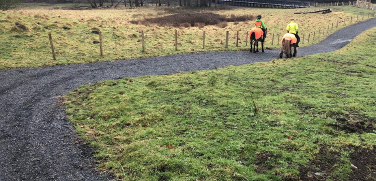 Two horseriders on horseback, wearing high vis, on the West Windermere Way.