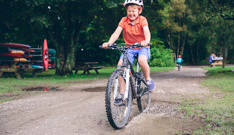 Child riding a bike through a puddle