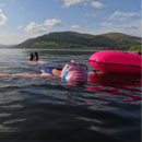 swimmer floating on her back with bright cap and  tow float for visibility