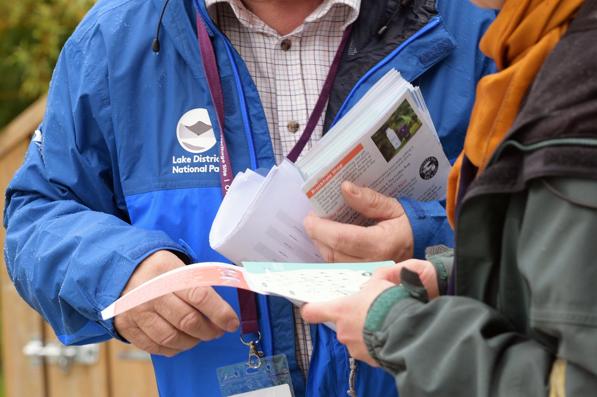 Image of two people cropped around mid-torso to show hands holding information books.