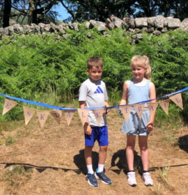 two children standing behind bunting that spells out Eskdale Trail 