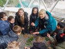A group of children crouching on the ground with Learning and Engagement Manager Ruth Suddaby, as they listen to her intently