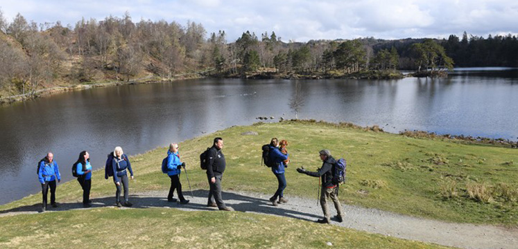 A volunteer leading a guided walk group at Tarn Hows in the Lake District