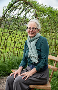 Alison Park sitting on a chair by a willow arbour