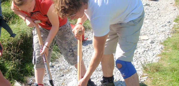 Two volunteers clearing footpath drains. 