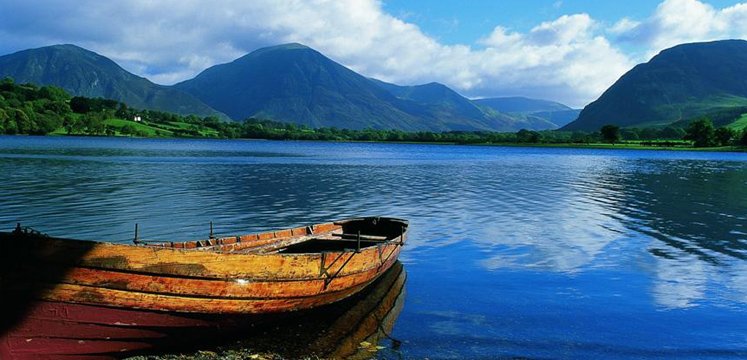 A wooden rowing boat on a lake shore